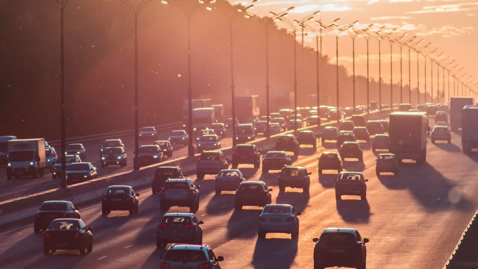 Rush-hour traffic filling every lane of a freeway into low sun