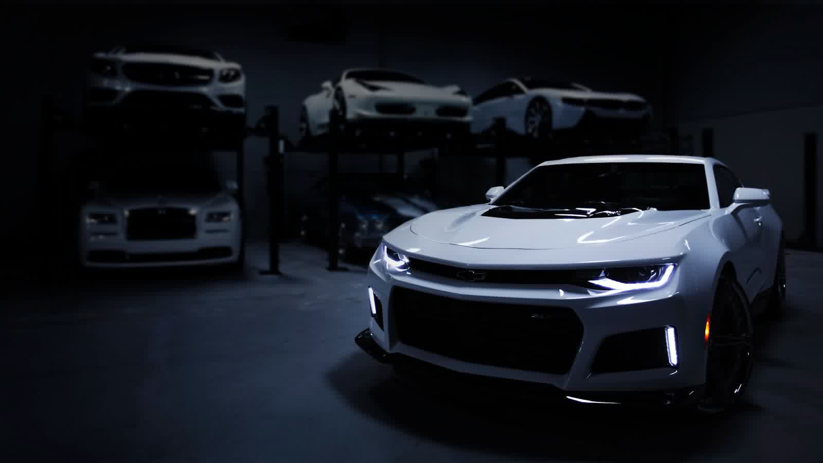 A silver muscle car under the spotlights of a dark studio