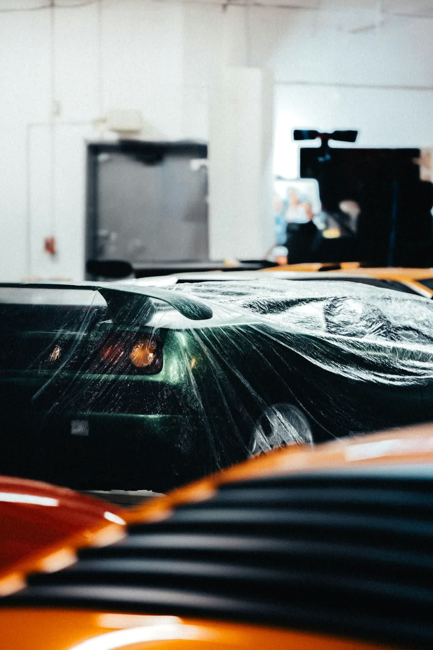 A dark green car in the bay under a full sheet of protection film
